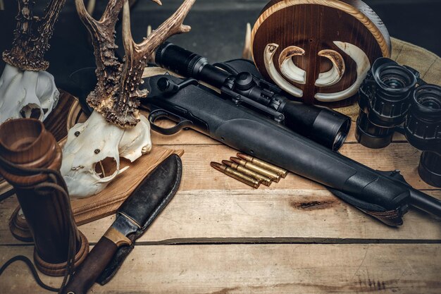 Munição de caça retrô de rifle e binóculos. Deliciosa salsicha e pão integral em uma mesa de madeira.