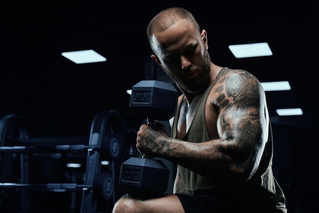 Musculoso esportista construindo bíceps com haltere