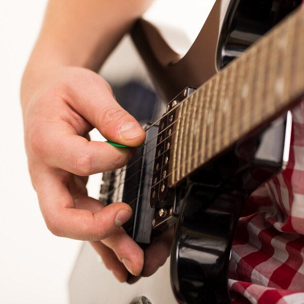 Música, close-up. Jovem músico segurando a guitarra electro