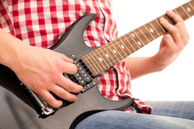 Música, close-up. Jovem músico segurando a guitarra electro