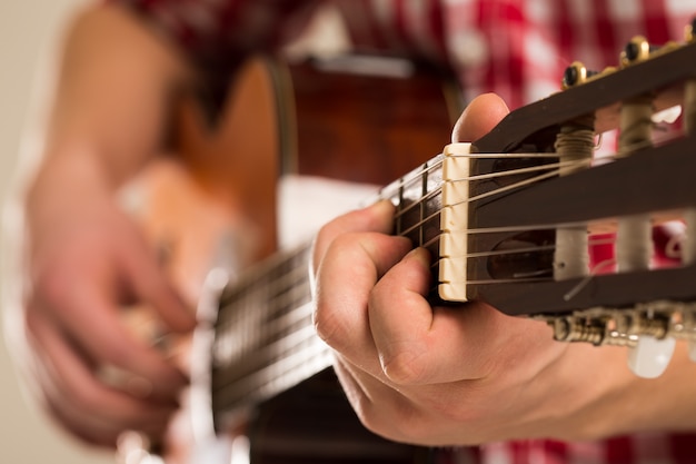Música, close-up. Músico segurando uma guitarra de madeira