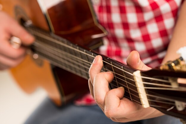 Música, close-up. Músico segurando uma guitarra de madeira