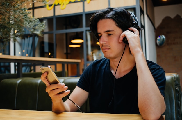 Música com fones de ouvido em uma cafeteria de menino