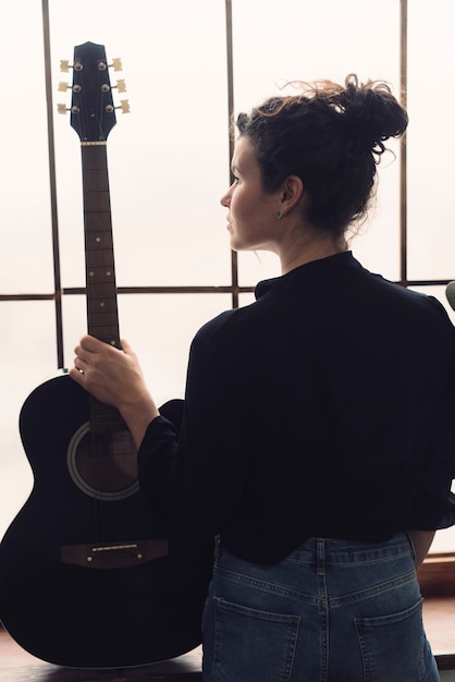 Foto grátis músico com guitarra na frente da janela