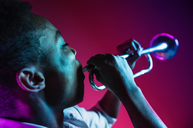 Músico de jazz tocando trompete no estúdio em uma parede de neon