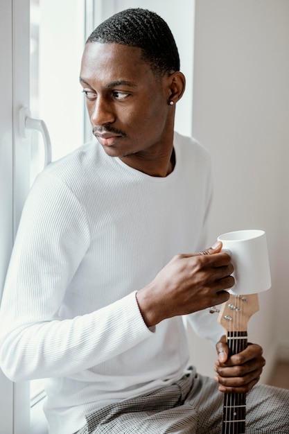 Músico segurando uma caneca e um violão