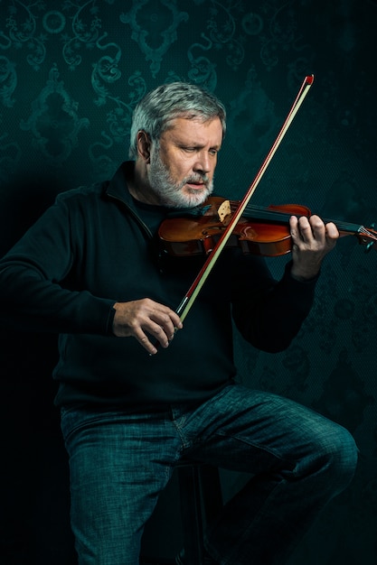 Foto grátis músico sênior tocando violino com varinha em preto