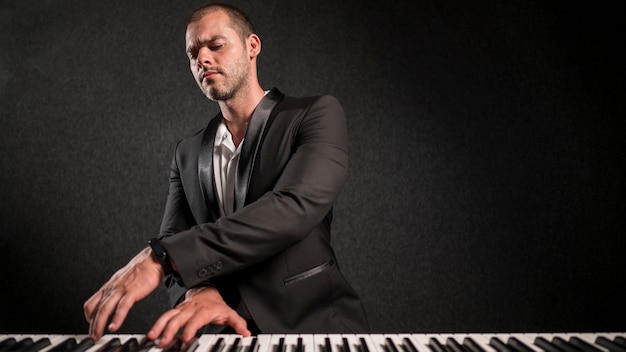 Músico vestido com elegância tocando teclado