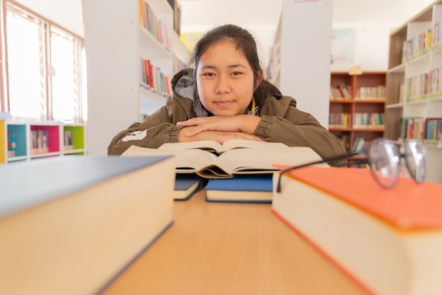 Na biblioteca - estudante jovem com livros que trabalham em uma biblioteca de ensino médio.