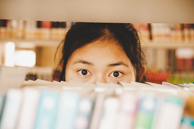 Na biblioteca - estudante jovem com livros que trabalham em uma biblioteca de ensino médio.