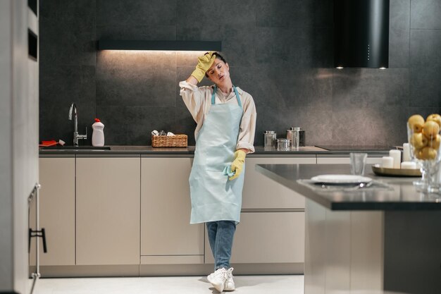 Na cozinha. Jovem de avental e luvas na cozinha