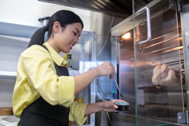 Na cozinha. Menina asiática trabalhando na cozinha e preparando comida