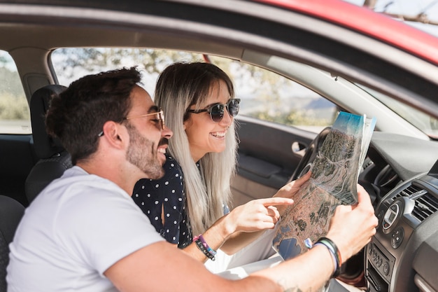 Foto grátis na moda jovem casal sentado dentro do carro olhando mapa