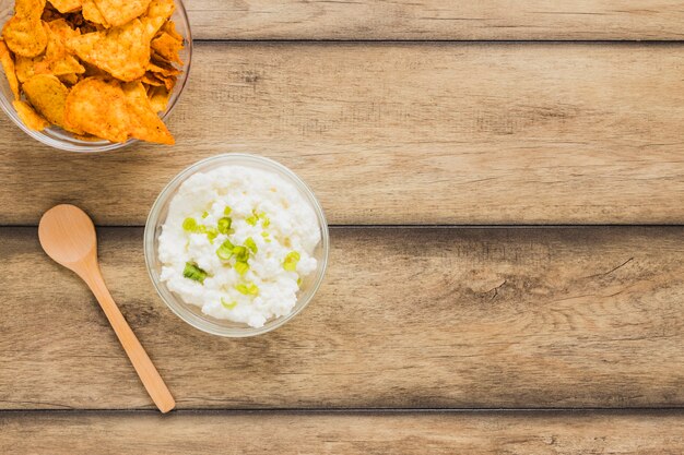 Nachos chips com queijo dip bowl e colher de pau na mesa