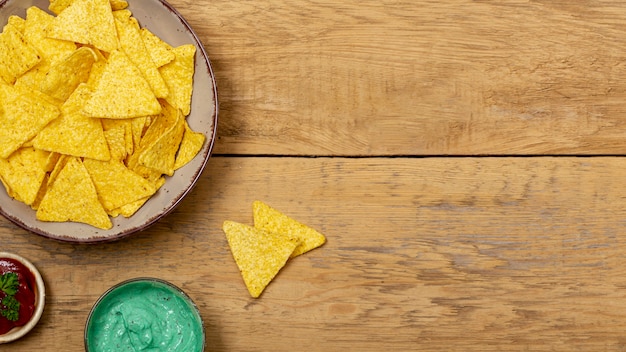 Nachos, molhos orgânicos e tomate na mesa de madeira