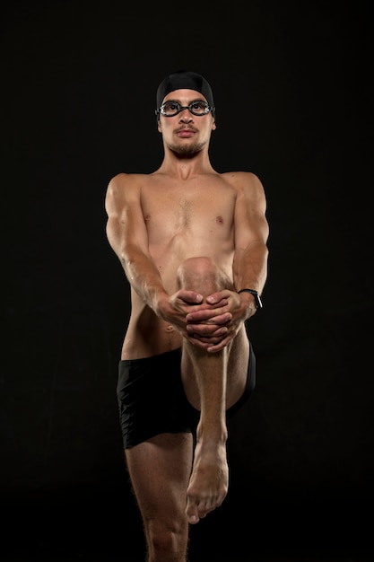 Nadador de tiro médio alongando as pernas