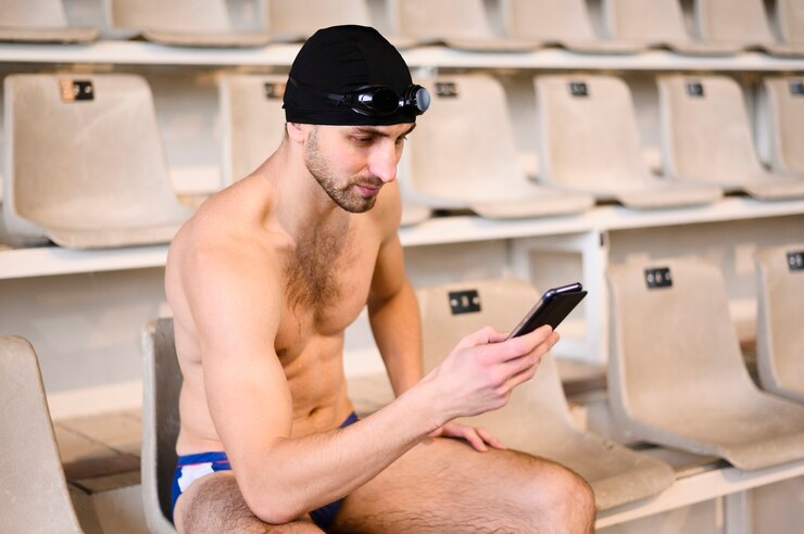 Foto grátis nadador masculino de alto ângulo no intervalo usando o celular