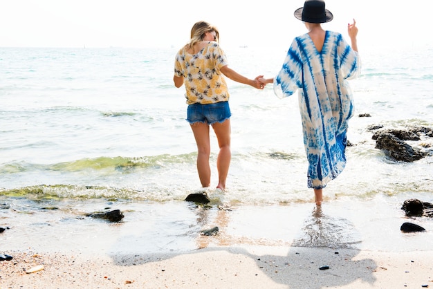 Namoradas de mãos dadas e andando na praia