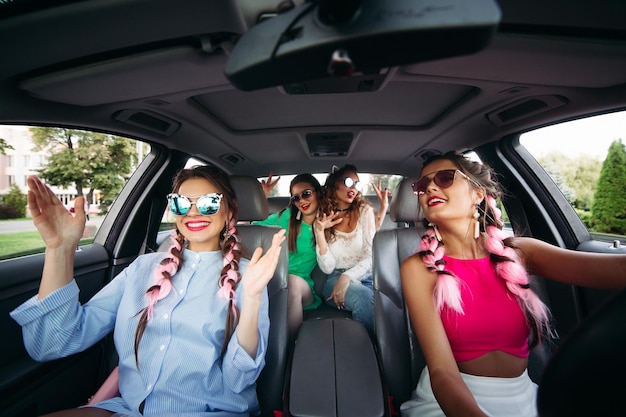 Namoradas modernas, elegantes e modernas vão no carro ouvindo música e se divertindo juntas. eles vão às compras para sua cidade. os amigos descansam juntos e as compras são sempre juntas.