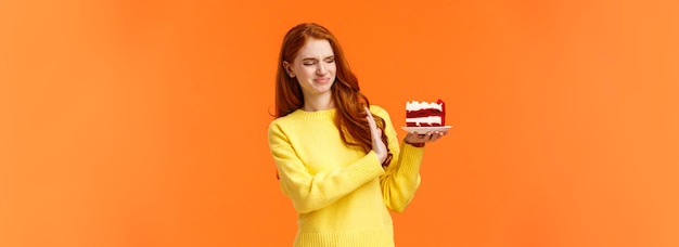 Foto grátis não, obrigado, não quero uma linda ruiva tentando resistir à tentação, morder doces deliciosos segurando ta