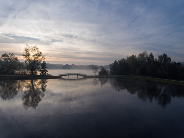 Nascer do sol com neblina sobre a água cercada por árvores na Holanda