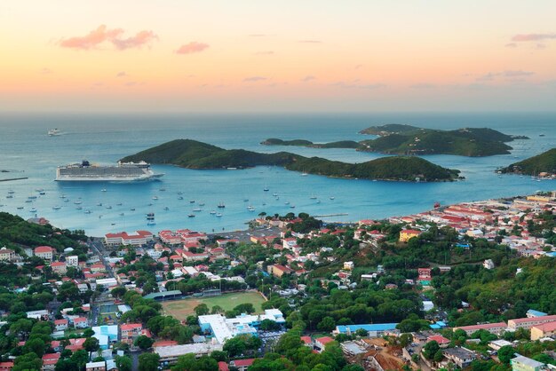Nascer do sol de St Thomas das Ilhas Virgens com nuvens coloridas, edifícios e litoral de praia.