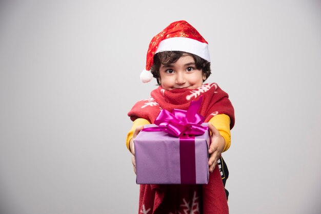 Natal com criança feliz oferecendo caixa de presente