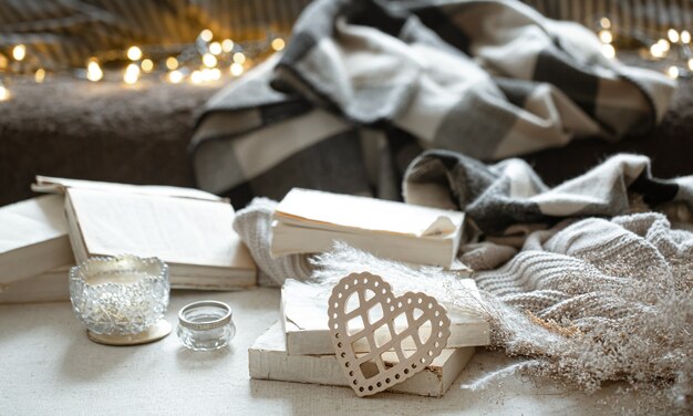 Natureza morta com coração decorativo, livros e coisas aconchegantes com bokeh. O conceito de dia dos namorados.