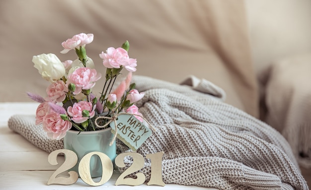 Natureza morta de páscoa com flores frescas da primavera em um vaso, tricotada com um elemento e número decorativo do ano 2021.