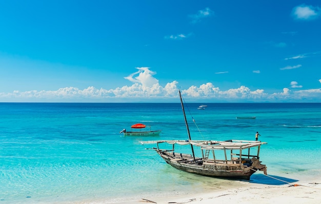 Navio de pesca de madeira na praia de areia branca na maré baixa, Oceano Índico. Zanzibar, Tanzânia