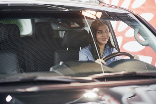 negócio automóvel, venda de carro, consumismo e conceito dos povos - mulher feliz que toma a chave do carro do negociante na feira automóvel ou salão de beleza