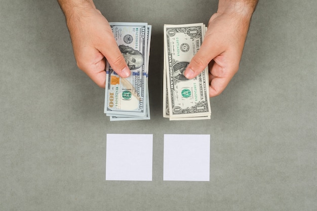 Foto grátis negócios e conceito de contabilidade com notas auto-adesivas, lupa na configuração de superfície cinza. homem segurando dinheiro dólares.