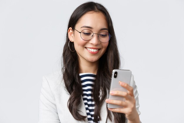 Negócios, finanças e emprego, conceito de empresárias de sucesso feminino. Close-up de elegante mulher de negócios moderna em terno e óculos enviando mensagens, usando telefone celular