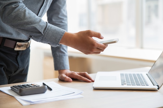 Negócios, segurando o smartphone em laptop no escritório