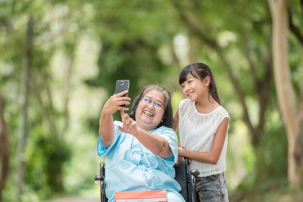 neta tirando uma foto com a avó em uma cadeira de rodas