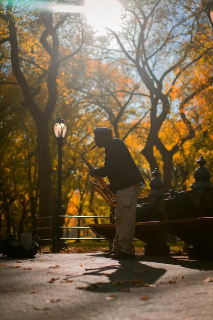 New York City Manhattan Central Park no outono. Um músico de rua toca saxofone no Central Park, em Nova York.