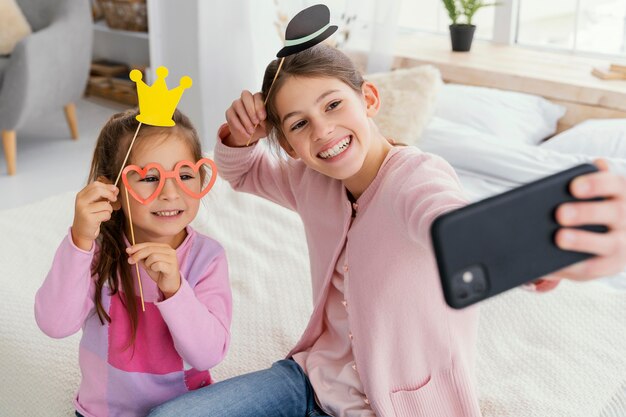 Ângulo alto de duas irmãs sorridentes em casa tirando uma selfie