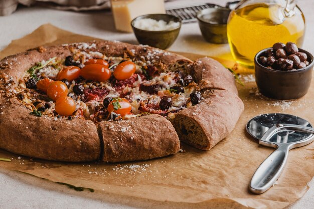 Ângulo alto de pizza deliciosa com cortador de pizza e tomates