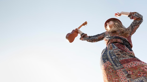 Ângulo baixo da mulher boêmia com espaço ukulele e cópia