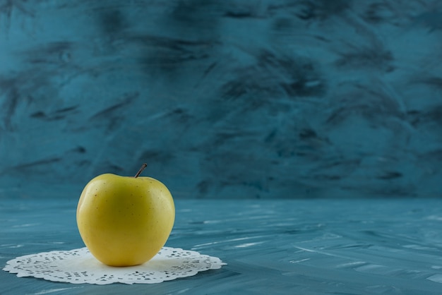 Única maçã orgânica fresca colocada na superfície azul.