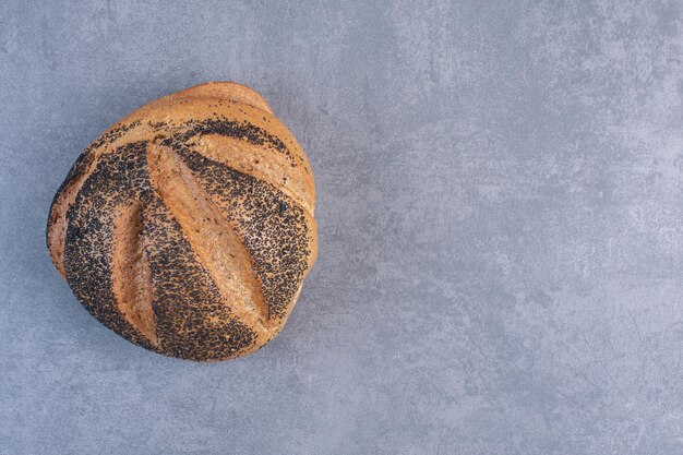 Único pedaço de pão revestido de gergelim preto no fundo de mármore. Foto de alta qualidade