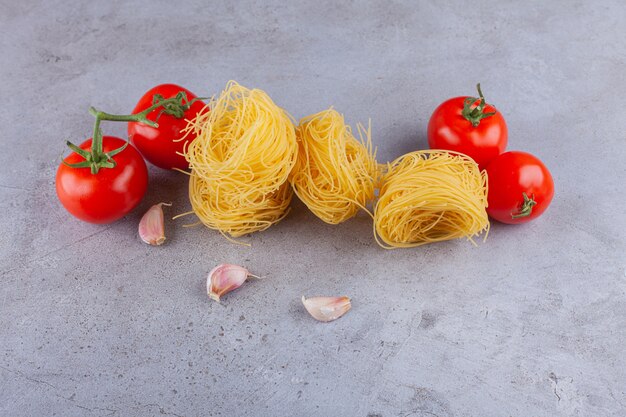 Ninho de fettuccine de massa italiana com tomates vermelhos frescos e dentes de alho.