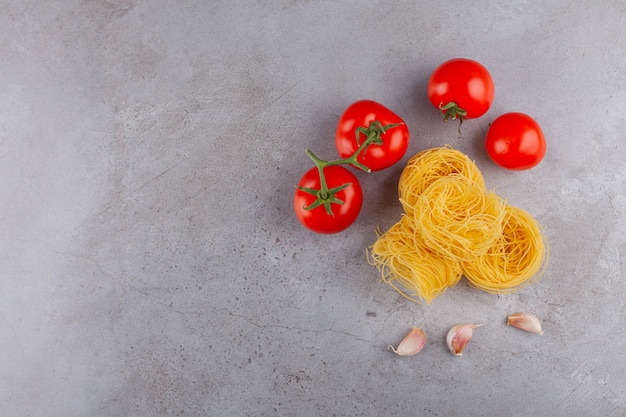 Ninho de fettuccine de massa italiana com tomates vermelhos frescos e especiarias.