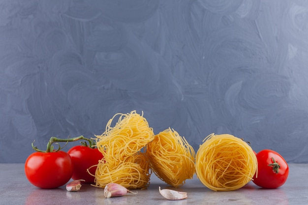 Ninho de fettuccine de massa italiana com tomates vermelhos frescos e especiarias.