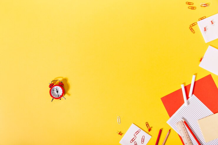 Foto grátis no centro da exposição do papelaria escolar está um pequeno despertador vermelho