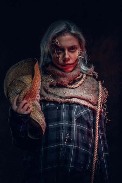 No estúdio fotográfico escuro, uma linda mulher com maquiagem assustadora está posando para o fotógrafo.