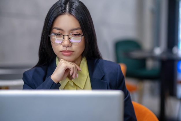 No trabalho. Mulher de negócios asiáticos no escritório trabalhando em um laptop