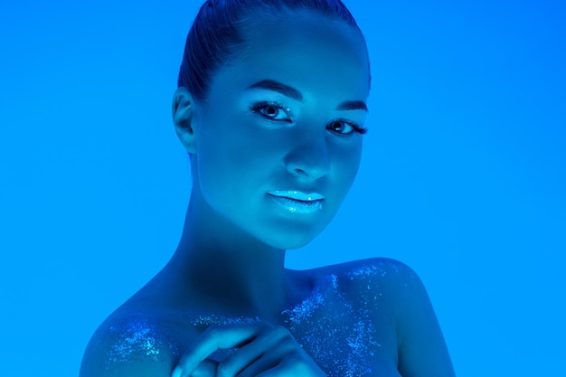 Noite. Retrato de mulher bonita isolado em azul em luz de néon, monocromático