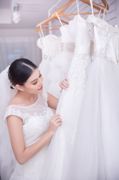 Noiva asiática jovem experimentando vestido de noiva no casamento moderno