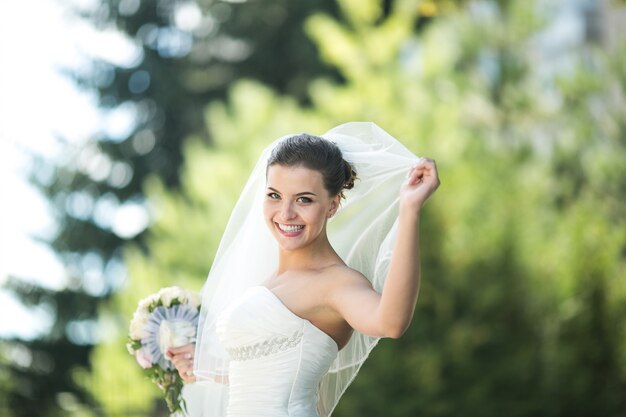 Noiva de sorriso que prende um ramalhete